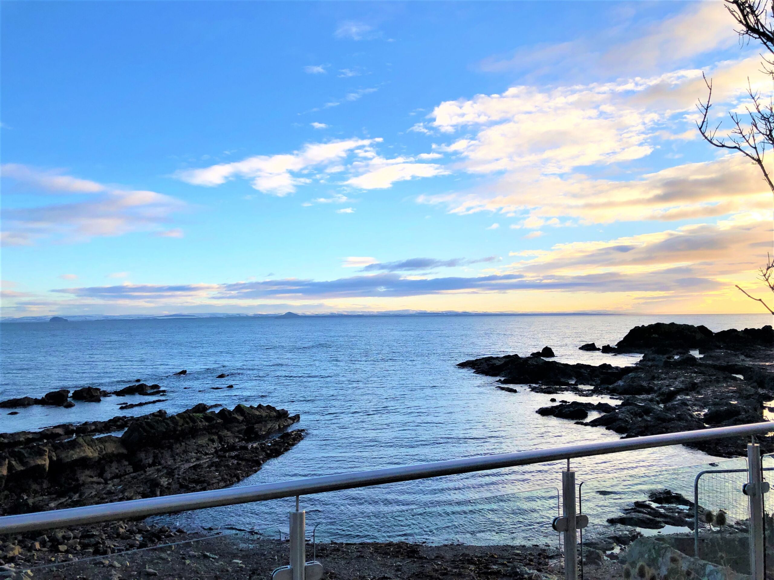 Railings overlooking a rocky cove at sunset