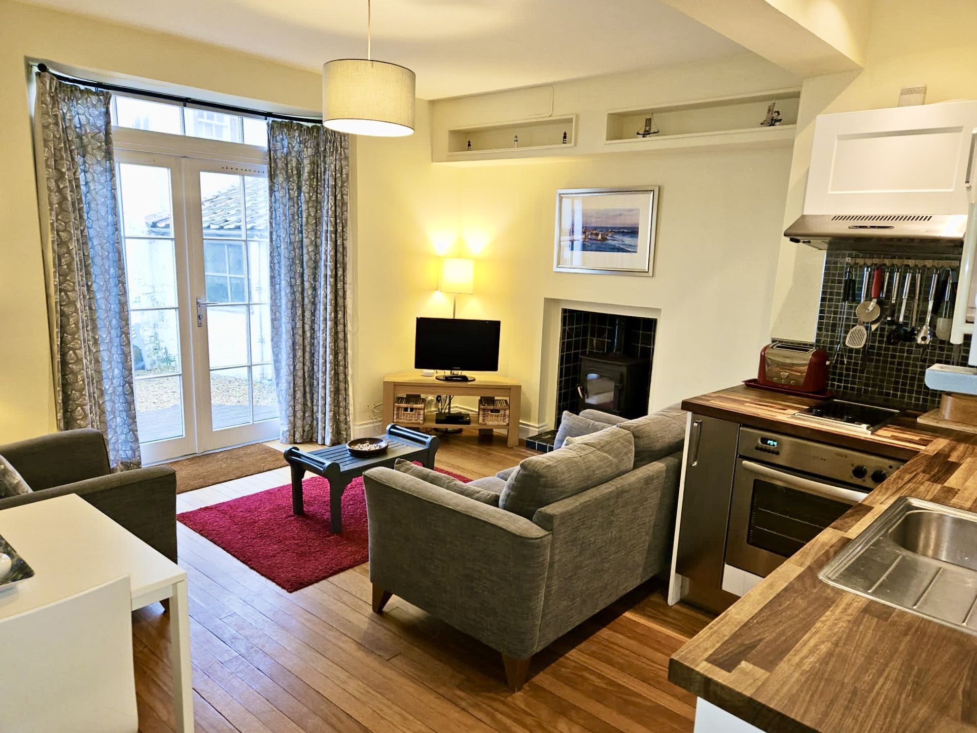 A living room with a kitchen area, fireplace, sofa and TV