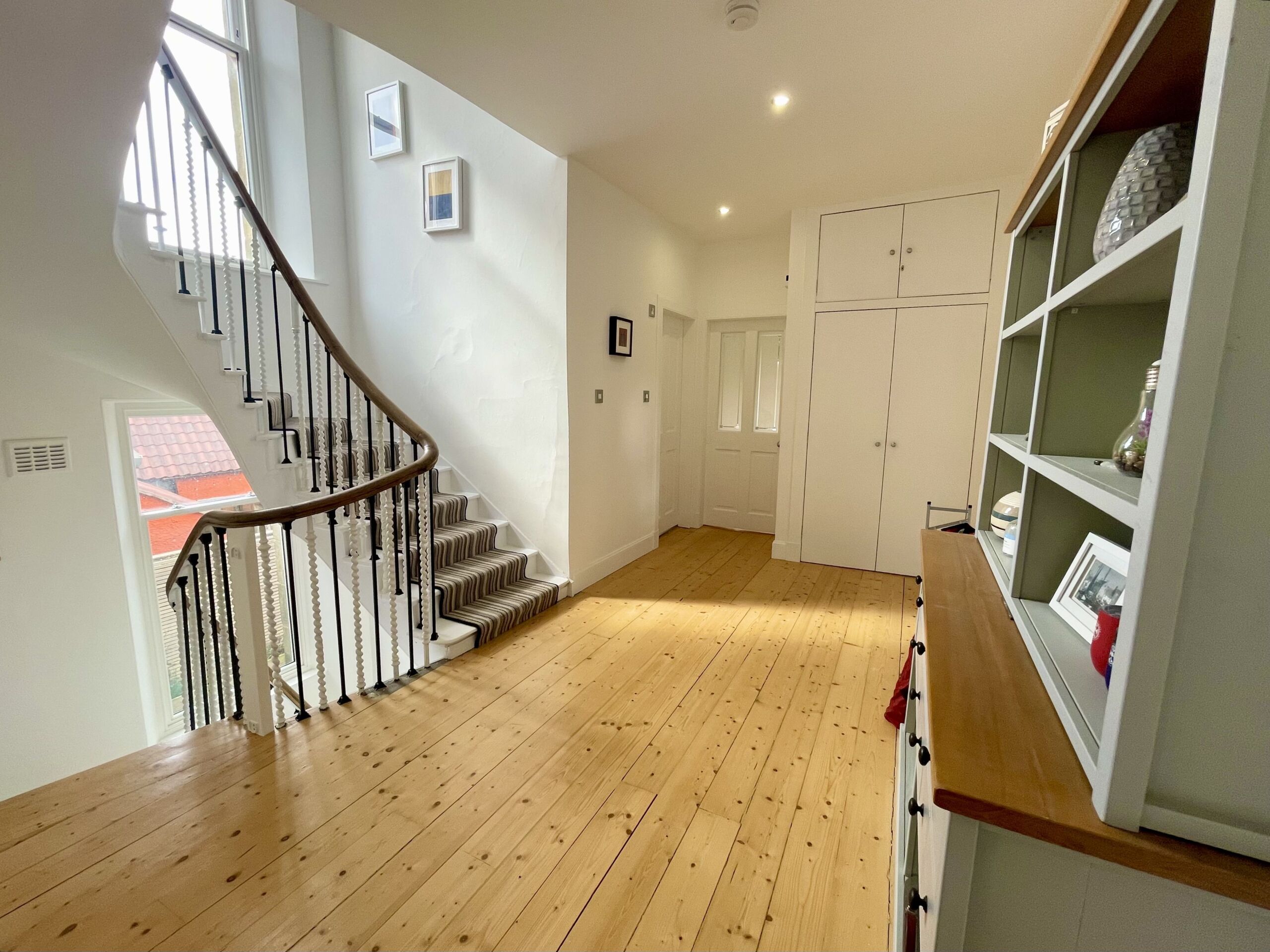 A room with wooden floors, stairs and a dresser