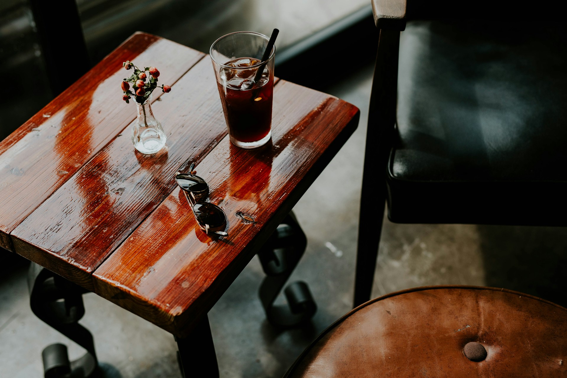 A drink in a glass on a wooden table with flowers