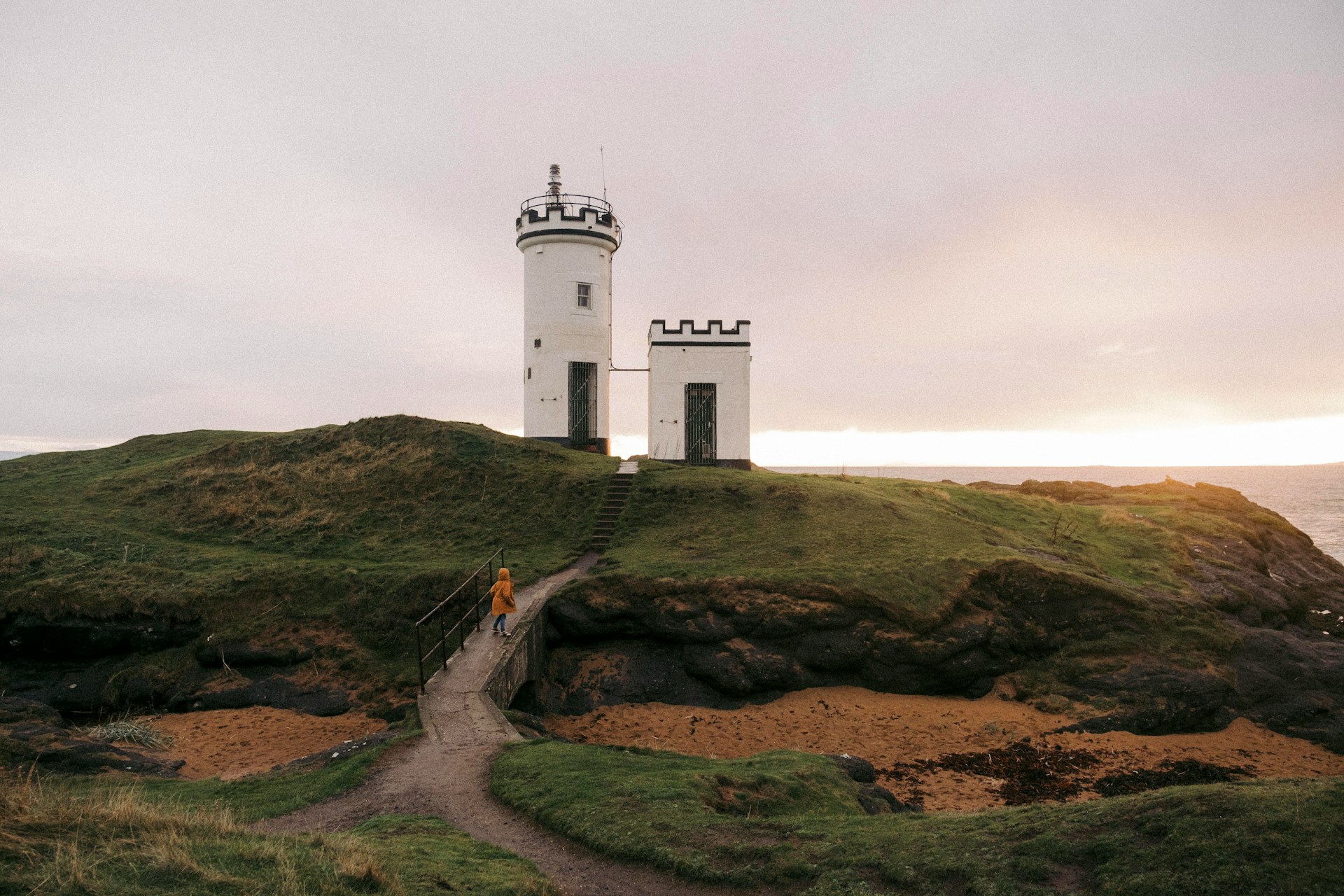 A lighthouse on top of a hill near the ocean