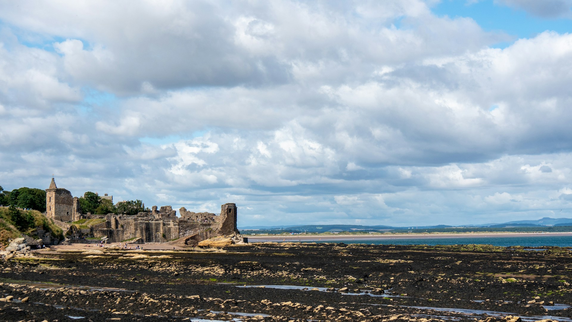 Brown ruins on the edge of a bay looking out to sea