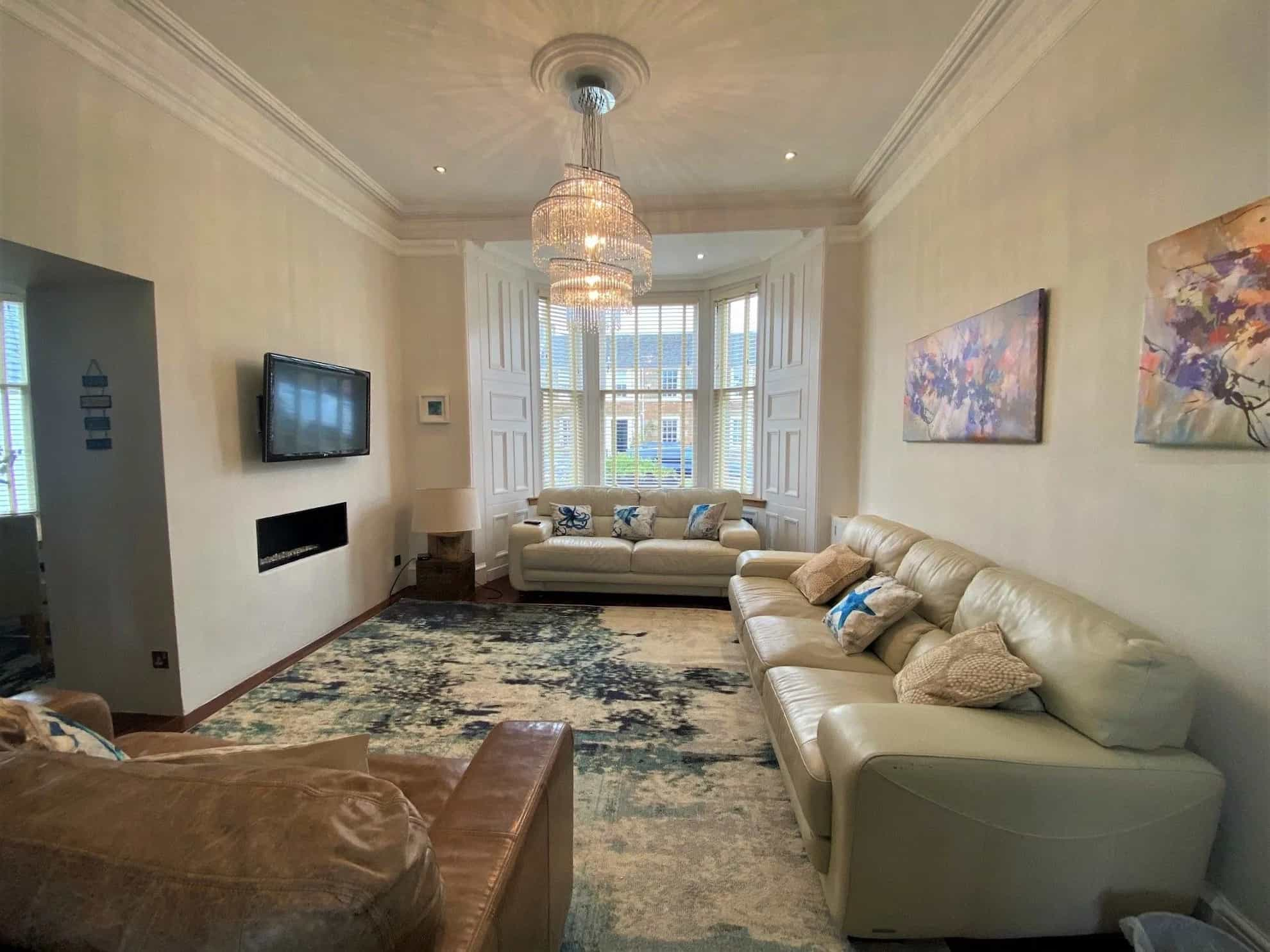 A large living room with cream sofas and a chandelier