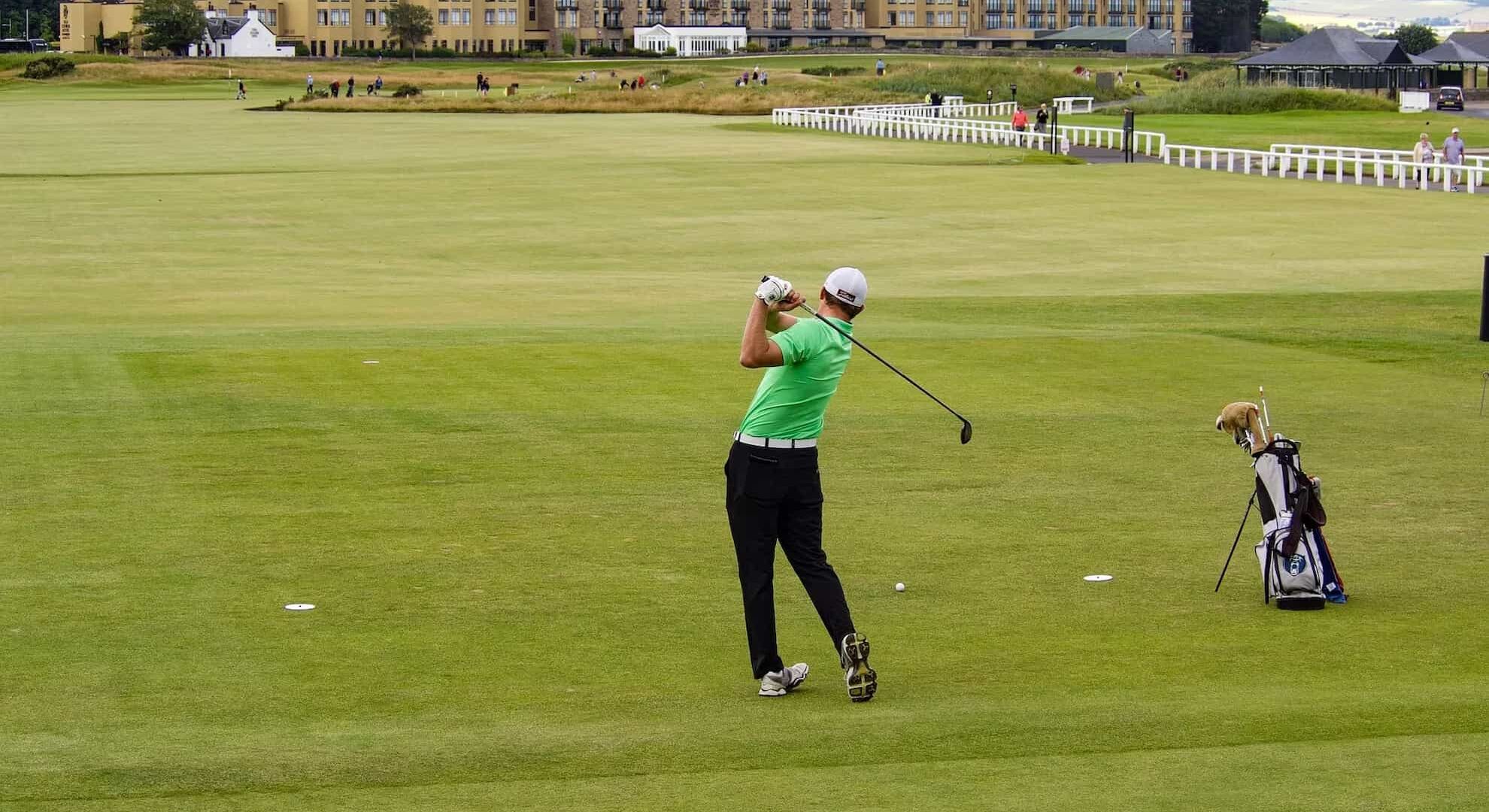 A man swinging a golf club on a green golf course