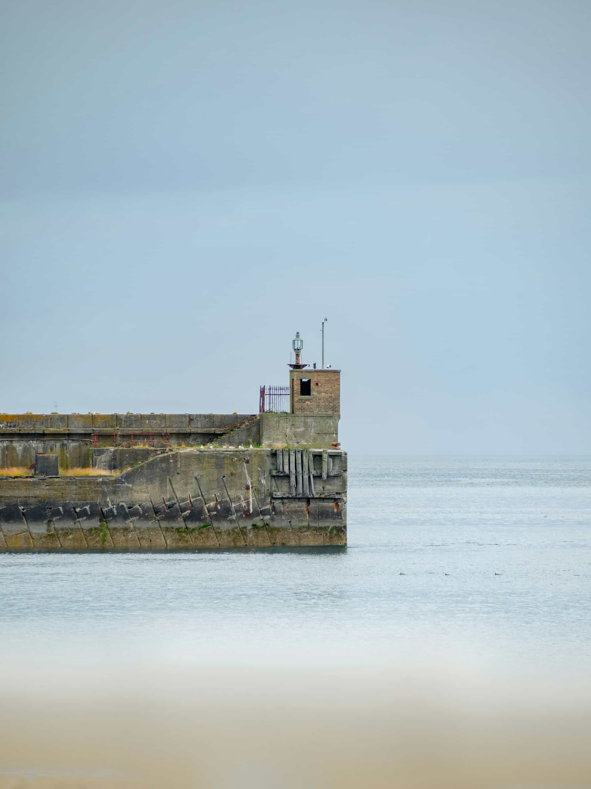 A stone jetty with a small lighthouse on the end