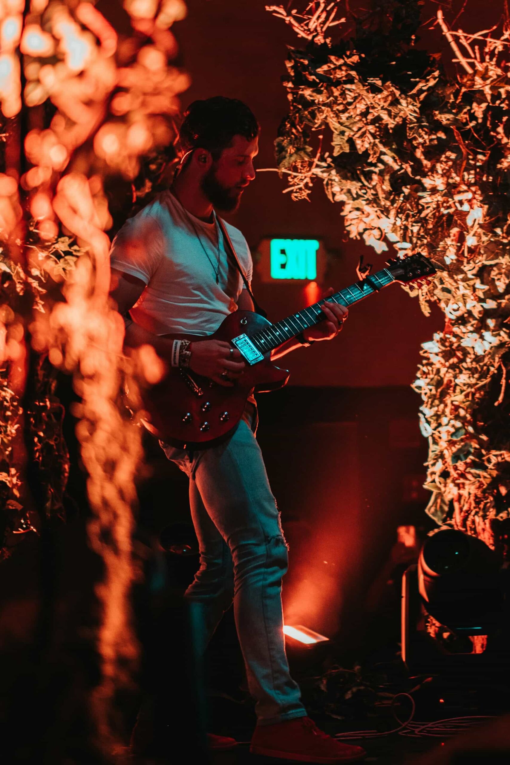 A man playing a guitar surrounded by plants