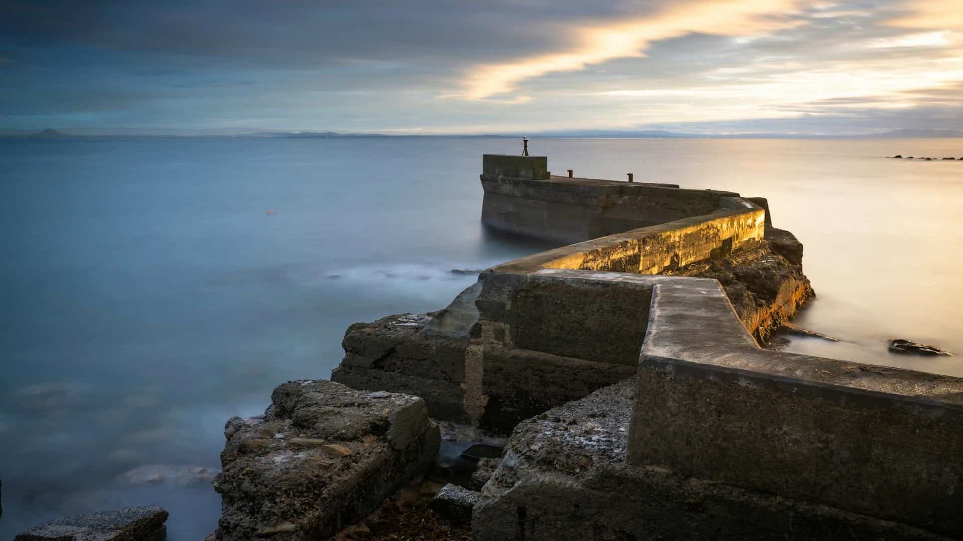 A long exposure image of the sea and a stone pier