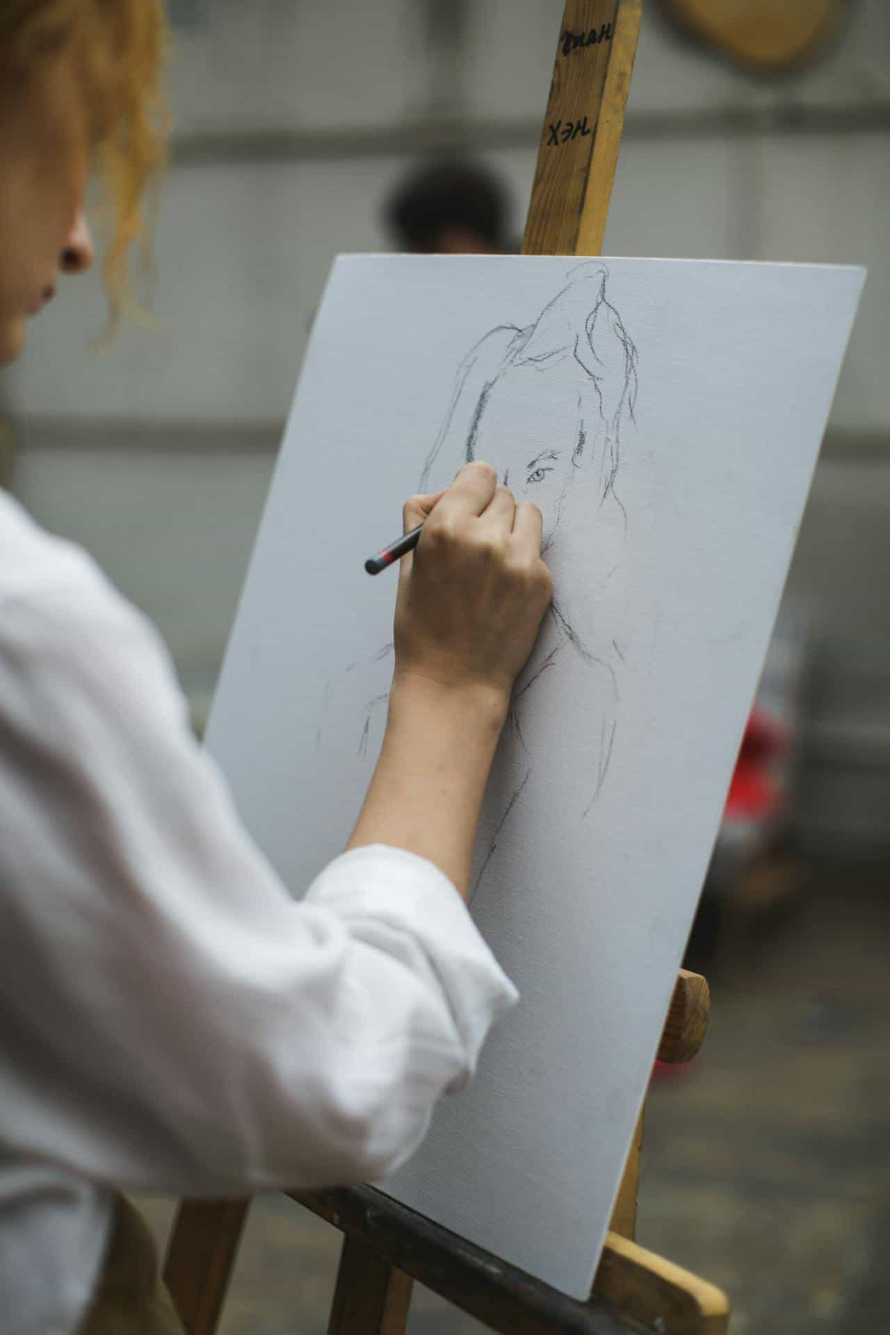 A woman in a white shirt drawing on paper