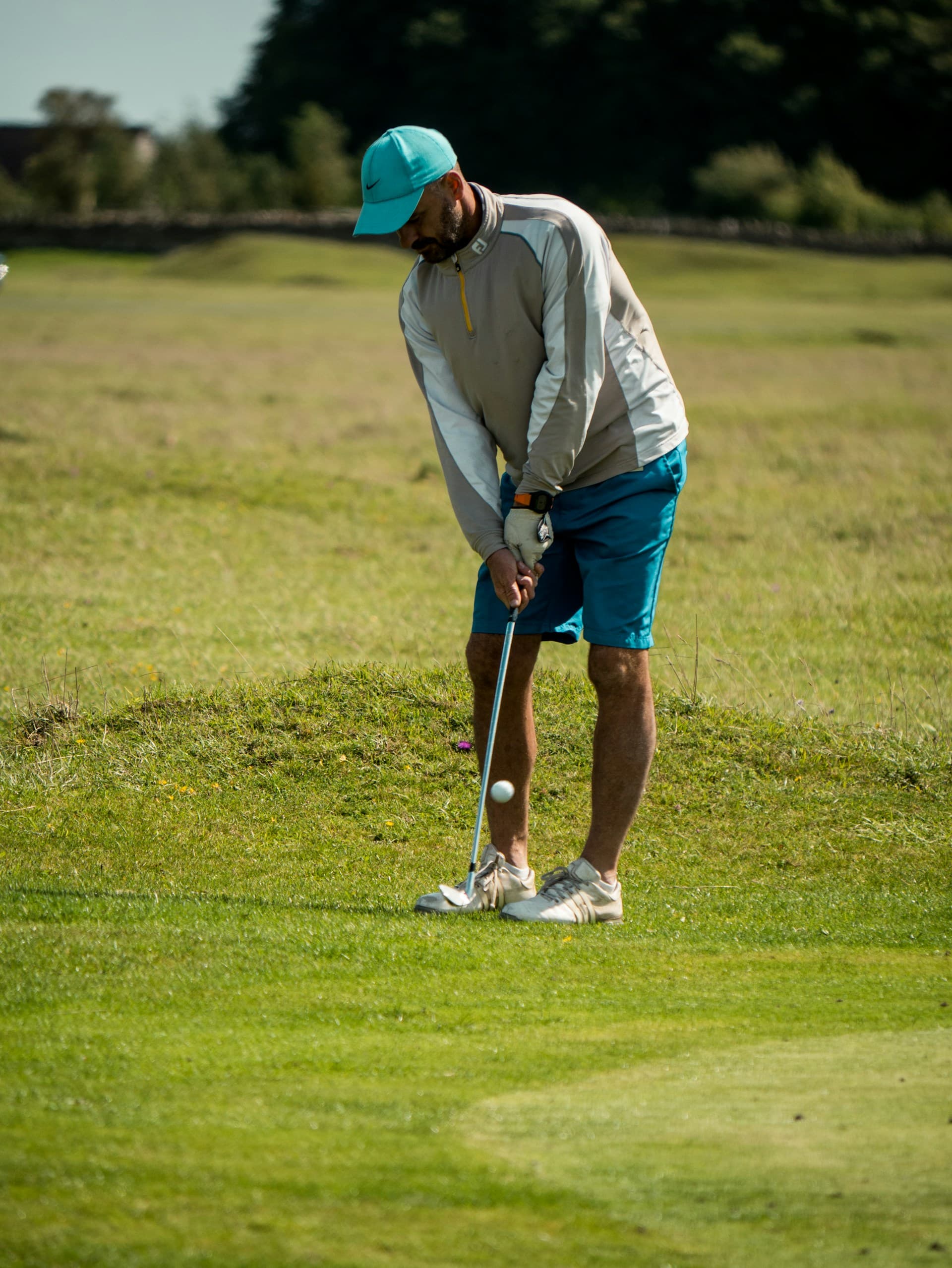 A man in a hat standing playing golf